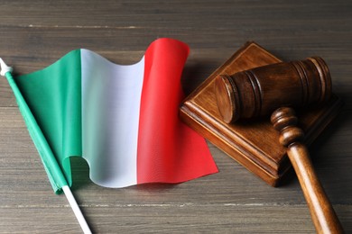 Photo of Judge's gavel and flag of Italy on wooden table, closeup