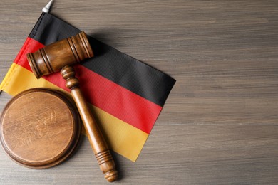 Photo of Judge's gavel and flag of Germany on wooden table, top view. Space for text