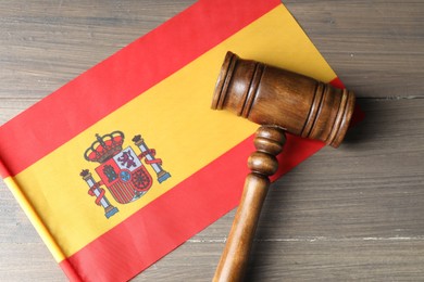 Photo of Judge's gavel and flag of Spain on wooden table, top view