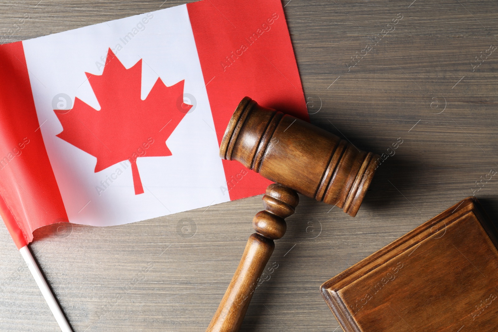 Photo of Judge's gavel and flag of Canada on wooden table, top view
