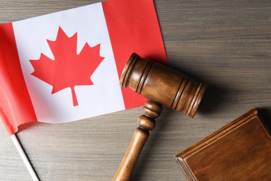 Photo of Judge's gavel and flag of Canada on wooden table, top view