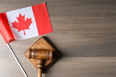 Photo of Judge's gavel and flag of Canada on wooden table, top view. Space for text