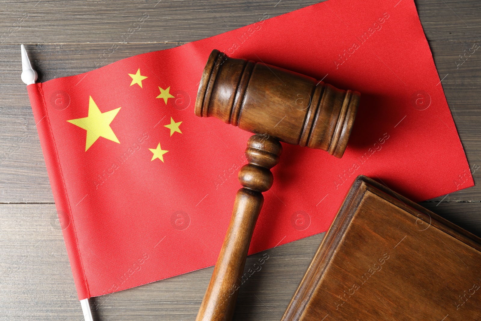 Photo of Judge's gavel and flag of China on wooden table, top view