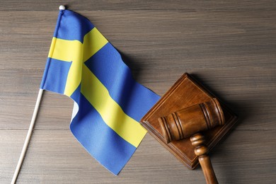 Photo of Judge's gavel and flag of Sweden on wooden table, top view