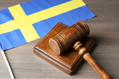 Photo of Judge's gavel and flag of Sweden on wooden table, closeup