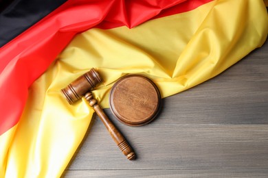 Photo of Judge's gavel and flag of Germany on wooden table, top view