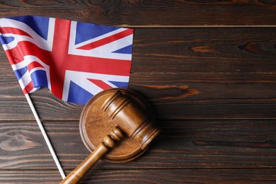 Photo of Judge's gavel and flag of United Kingdom on wooden table, top view. Space for text