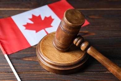 Photo of Judge's gavel and flag of Canada on wooden table, closeup