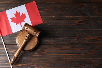 Photo of Judge's gavel and flag of Canada on wooden table, top view. Space for text