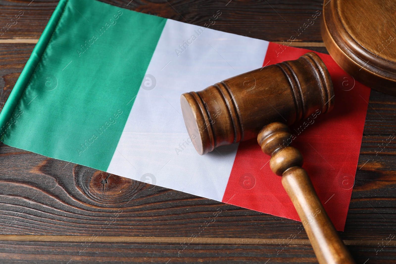 Photo of Judge's gavel and flag of Italy on wooden table, closeup