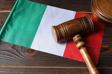 Photo of Judge's gavel and flag of Italy on wooden table, closeup