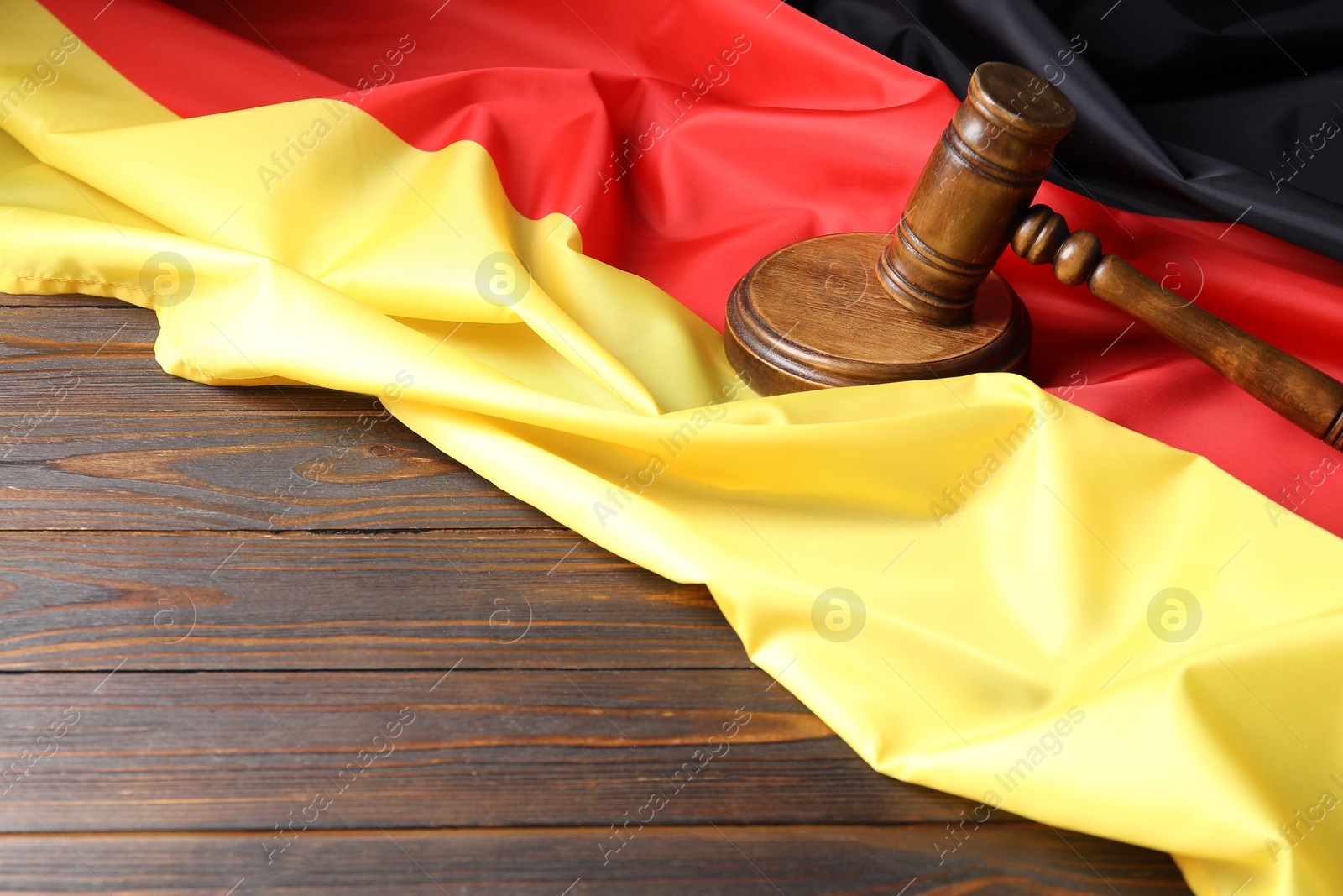 Photo of Judge's gavel and flag of Germany on wooden table. Space for text