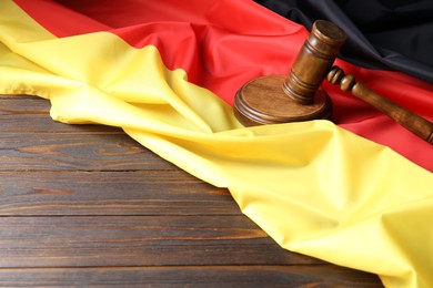 Photo of Judge's gavel and flag of Germany on wooden table. Space for text