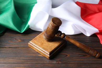 Photo of Judge's gavel and flag of Italy on wooden table
