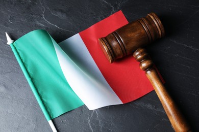 Photo of Judge's gavel and flag of Italy on black table, top view