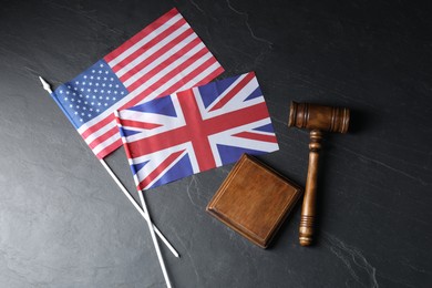 Photo of Judge's gavel and flags of USA and United Kingdom on black table, top view