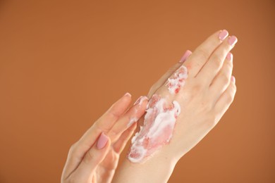 Photo of Woman applying healing cream onto burned hand on brown background, closeup. Space for text