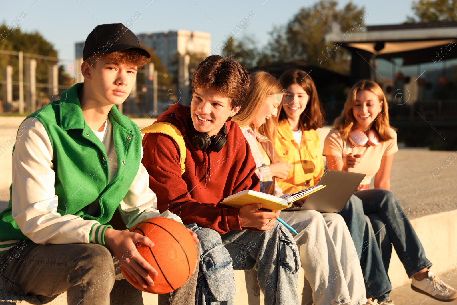 Photo of Group of teenagers doing homework together outdoors, selective focus