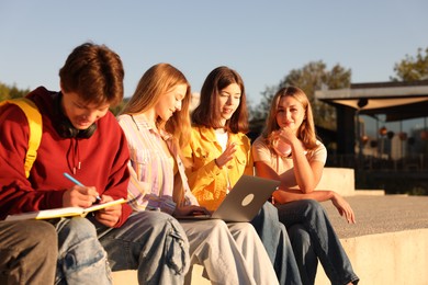 Photo of Group of teenagers doing homework together outdoors