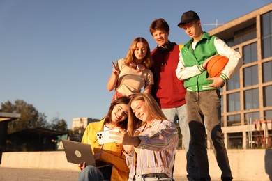 Photo of Group of teenagers taking selfie outdoors on sunny day, low angle view. Space for text