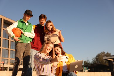 Photo of Group of teenagers taking selfie outdoors on sunny day, low angle view. Space for text