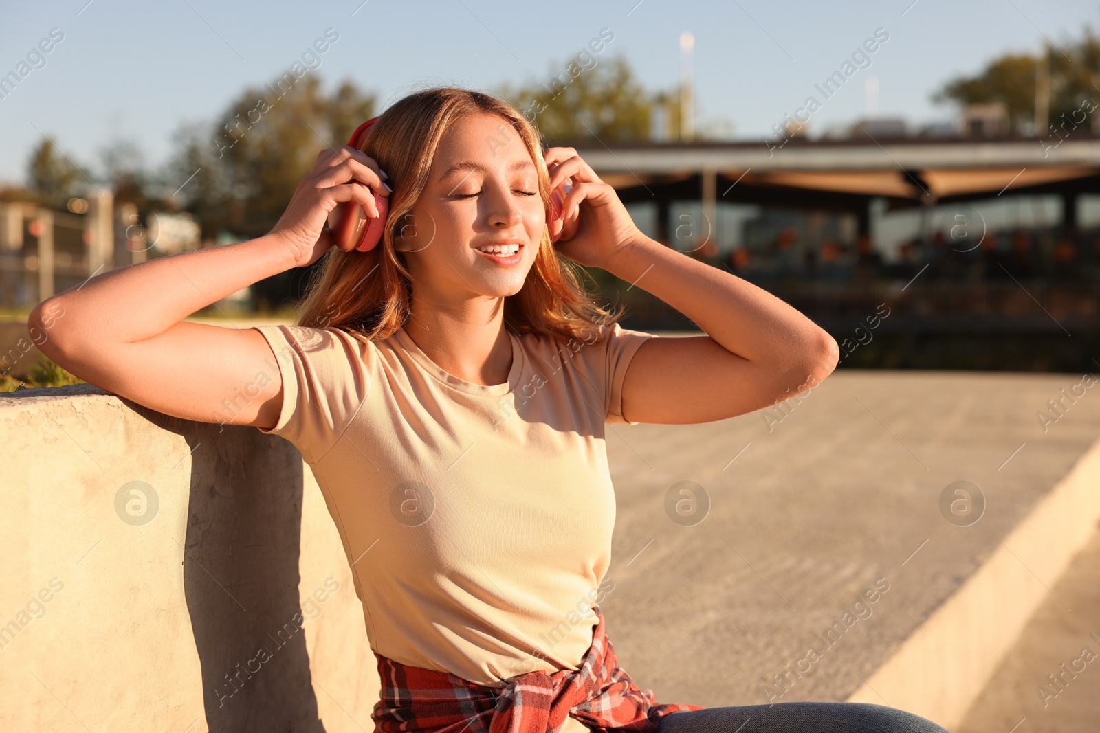 Photo of Teenage girl with headphones outdoors on sunny day