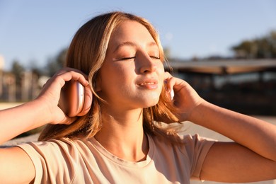 Photo of Teenage girl with headphones outdoors on sunny day