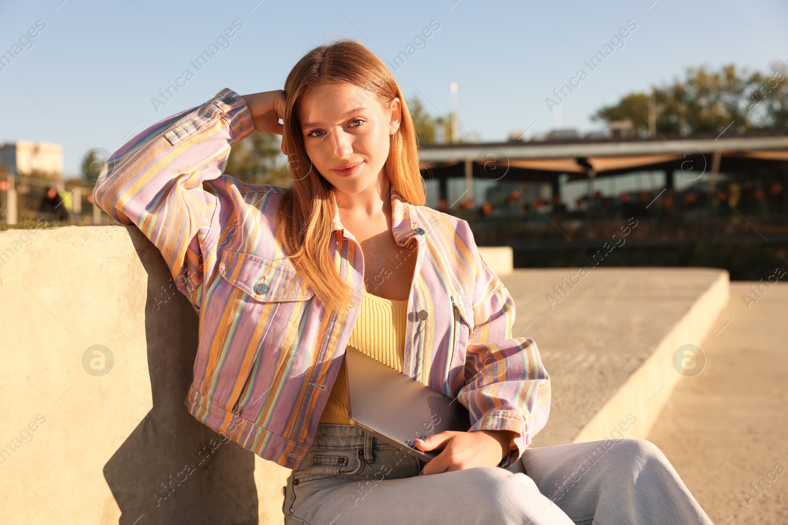 Photo of Teenage girl with laptop outdoors on sunny day
