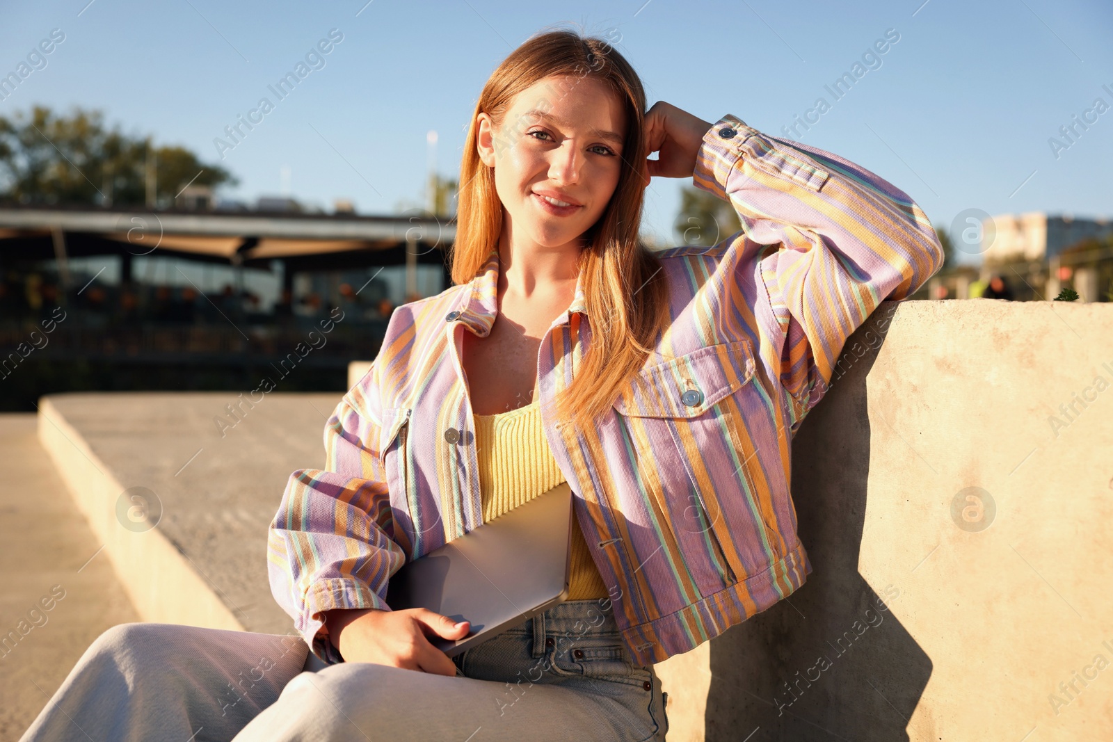 Photo of Teenage girl with laptop outdoors on sunny day
