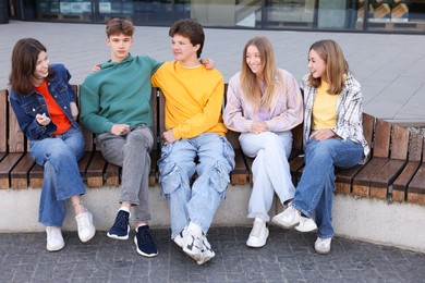 Photo of Group of teenagers sitting on bench outdoors