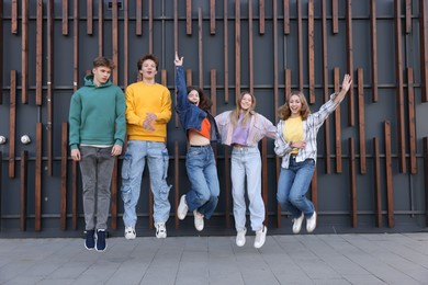 Photo of Group of teenagers jumping near building on city street