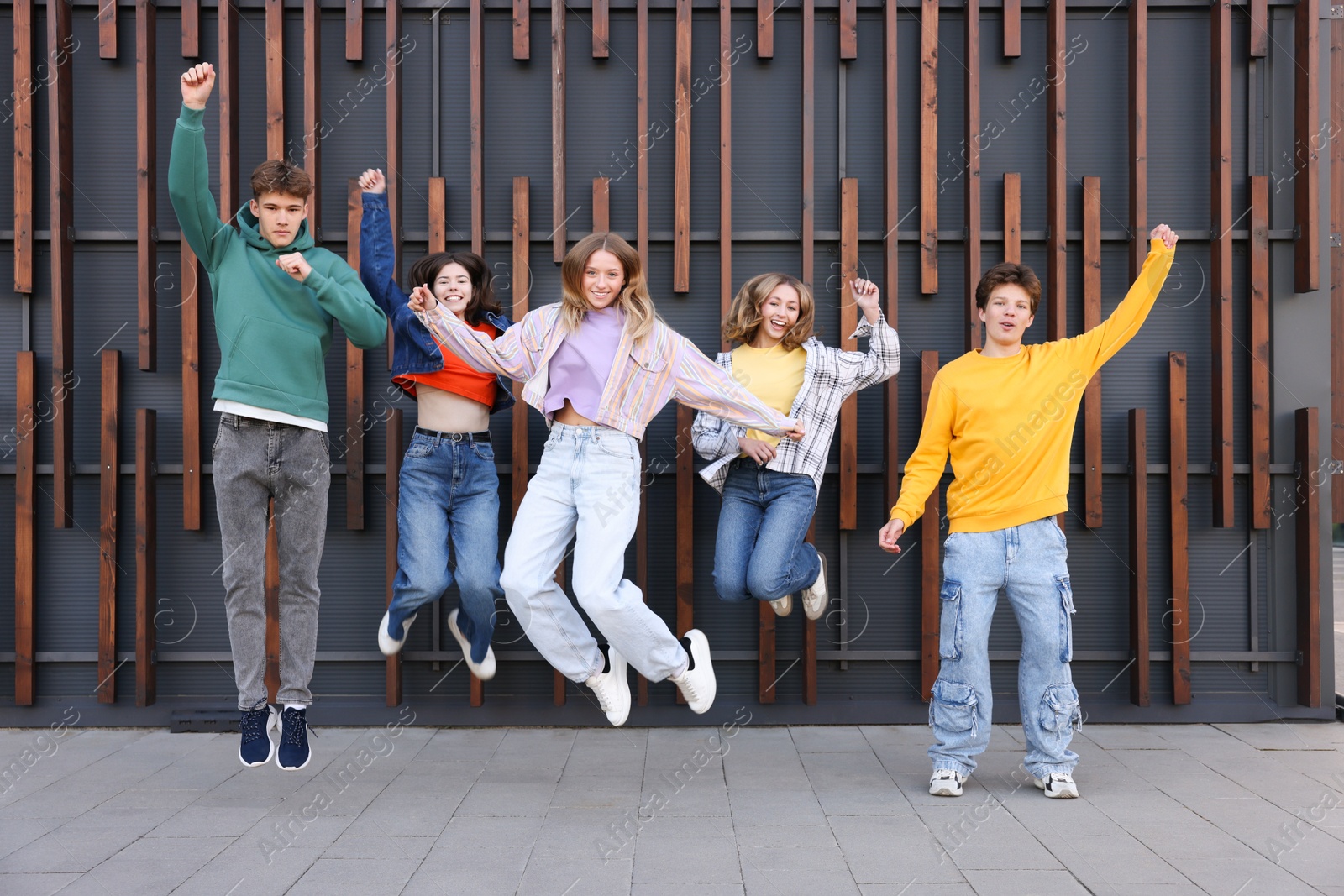 Photo of Group of teenagers jumping near building on city street