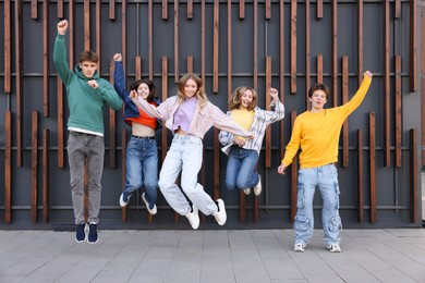 Photo of Group of teenagers jumping near building on city street