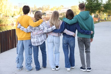 Photo of Group of teenagers walking on city street, back view
