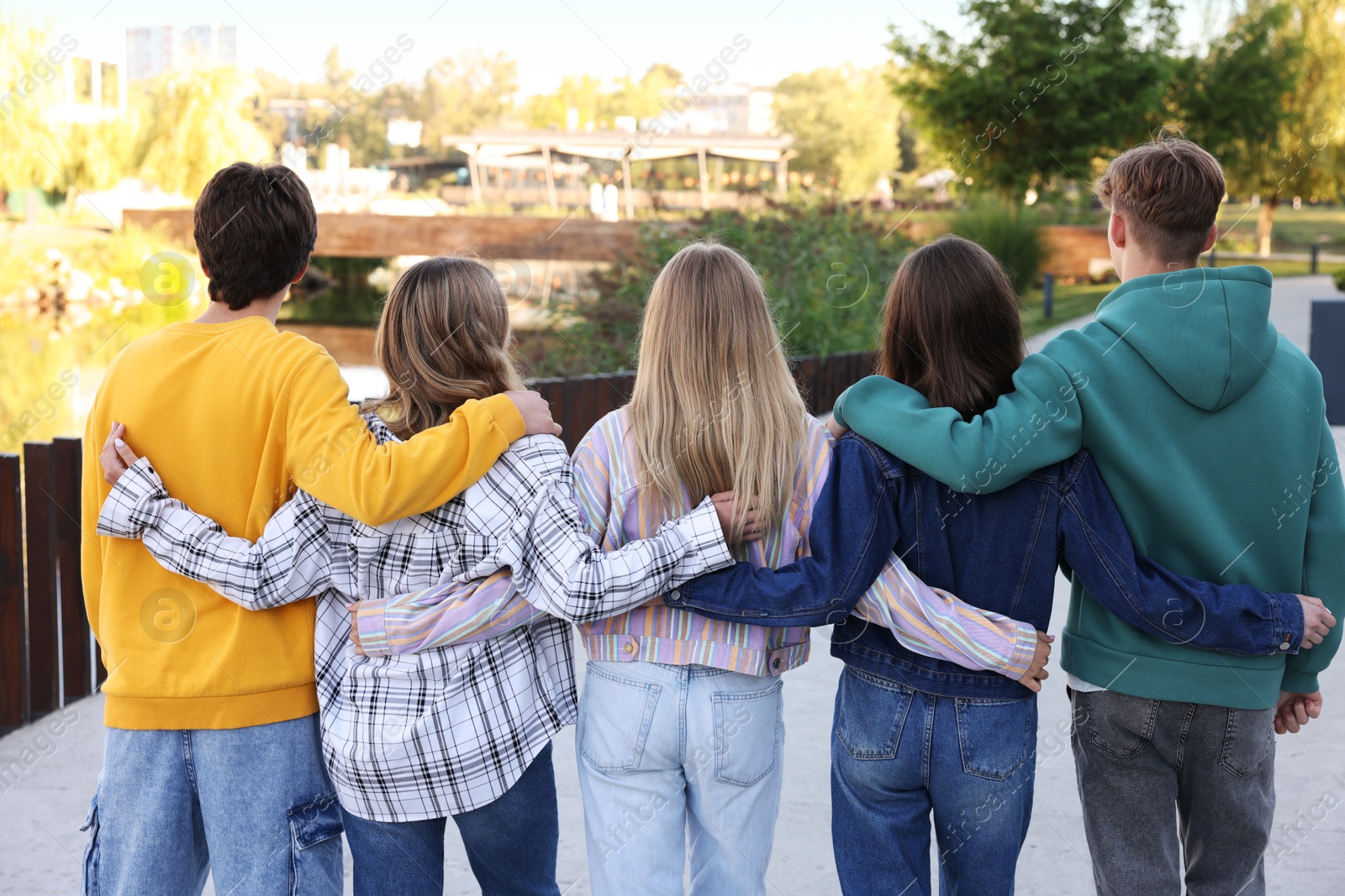 Photo of Group of teenagers walking on city street, back view