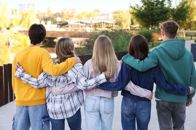 Photo of Group of teenagers walking on city street, back view