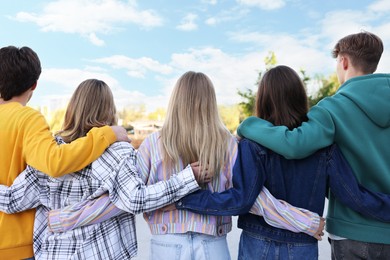 Photo of Group of teenagers walking on city street, back view