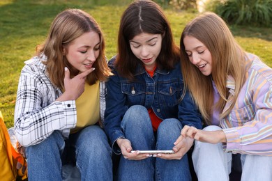 Photo of Teenagers watching something on smartphone in park