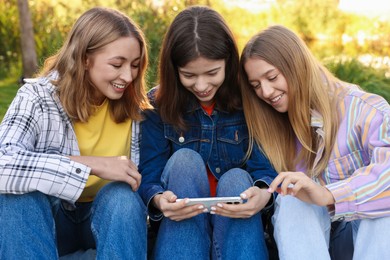 Photo of Teenagers watching something on smartphone in park