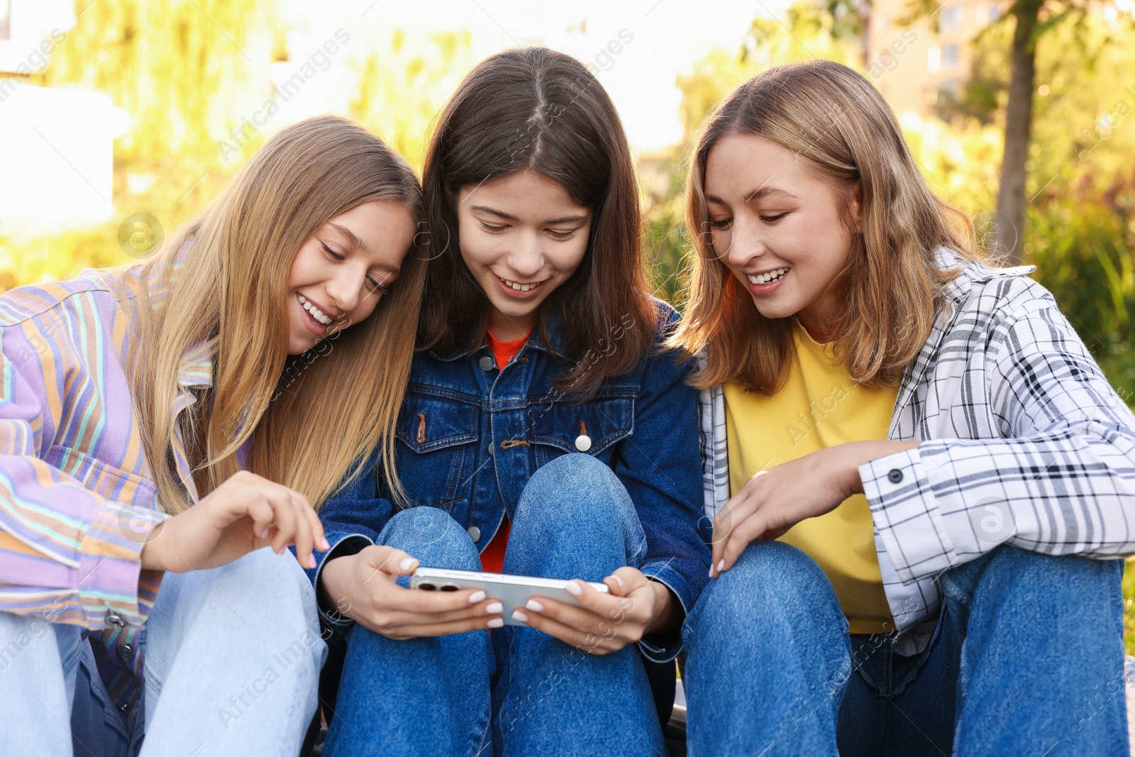 Photo of Teenagers watching something on smartphone in park