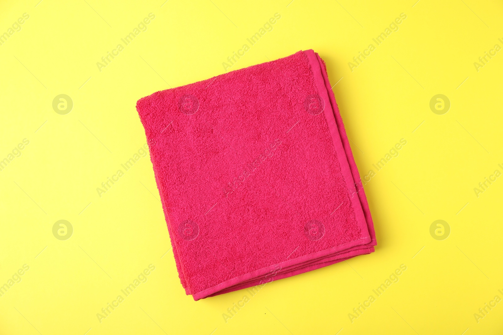 Photo of Red terry towel on yellow background, top view
