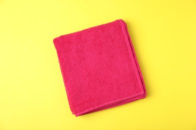 Photo of Red terry towel on yellow background, top view
