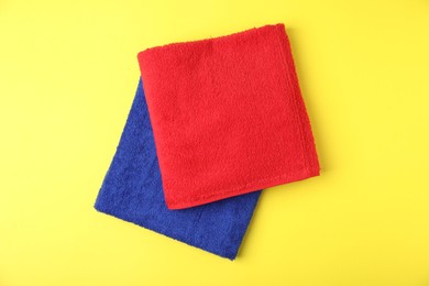 Photo of Bright terry towels on yellow background, top view