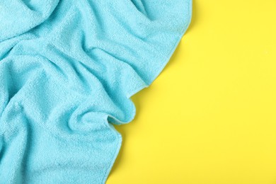 Photo of Light blue terry towel on yellow background, top view. Space for text