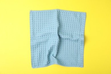 Photo of Light blue waffle towel on yellow background, top view