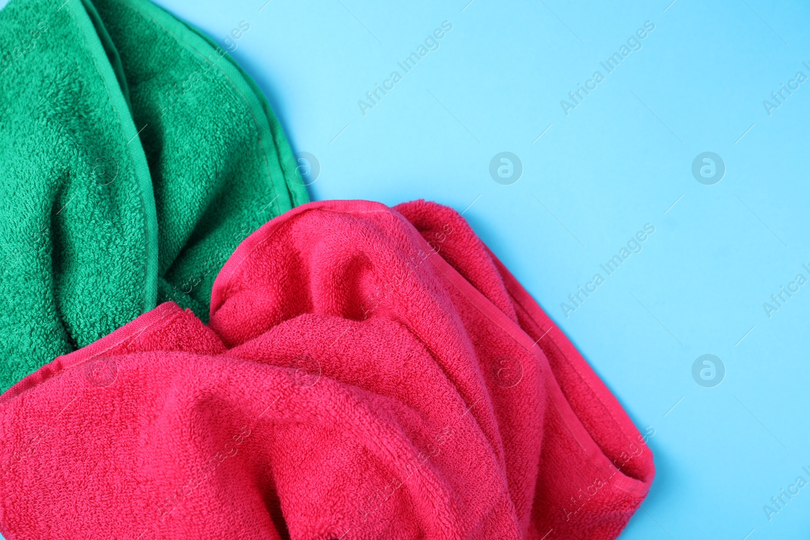 Photo of Bright terry towels on light blue background, above view. Space for text