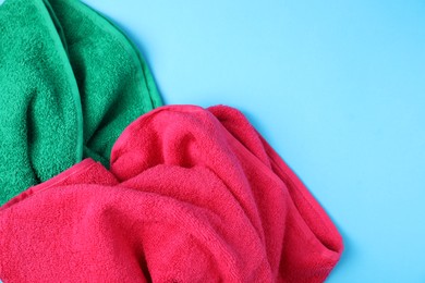 Photo of Bright terry towels on light blue background, above view. Space for text