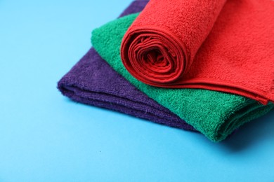 Photo of Clean terry towels on light blue background, closeup. Space for text