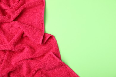 Photo of Red terry towel on green background, top view. Space for text
