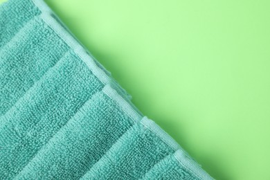 Photo of Turquoise terry towel on green background, top view. Space for text